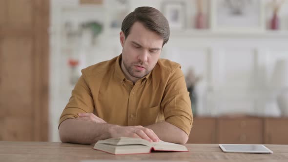 Young Man Reading Book while Sitting in Office