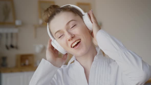 A Woman Lying on the Bed Listens To Music with Wireless Headphones and Relaxes. The Woman Dances and