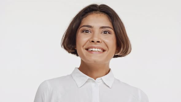 Young Beautiful East Asian Female in Shirt Suprisingly Smiling Twice on White Background