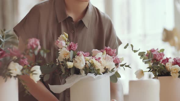 Female Florist Checking Composition in Hatbox and Smelling Flowers