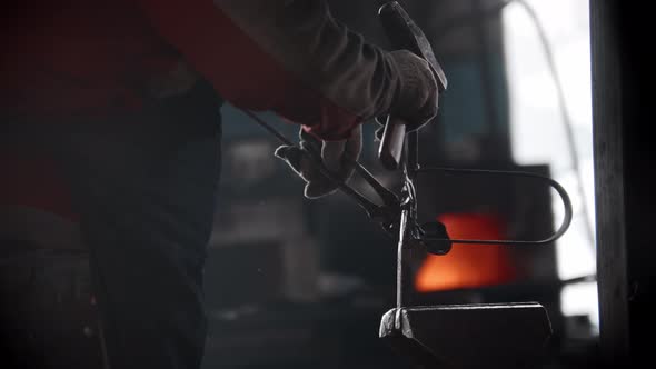 Blacksmith Workshop a Man Puts Metal Detail in the Pressing Retainer and Hits It with a Hammer