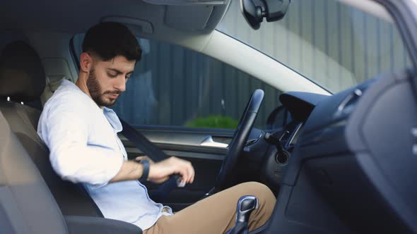 Bearded Man Fastens Car Seat Belt With Hand Compliance With Safety Rules for Driving