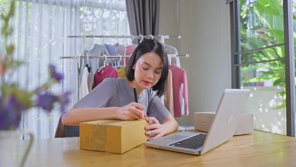 Work from home, Asian young beautiful woman using computer to sell cloth online feel happy.