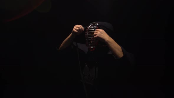 Athletic Kendo Warrior Is Putting on Helmet and Lacing It.