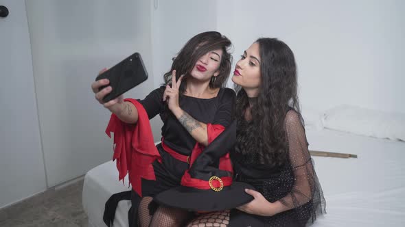 Two Attractive Colombian Women In Black Witch Costumes Taking Selfies Using A Smartphone At The