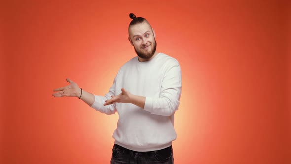 Man Points Hands Aside and Pretends He Gives Something on Red Background