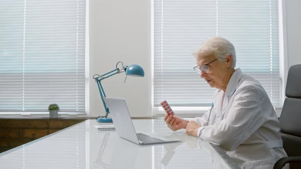 Senior lady doctor with glasses shows blister