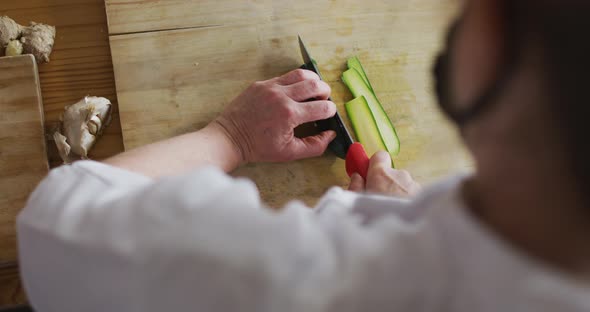 Caucasian female chef cutting zucchini