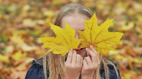 A Young Girl of 13 Years Old with Autumn Leaves Poses in Front of a Video Camera