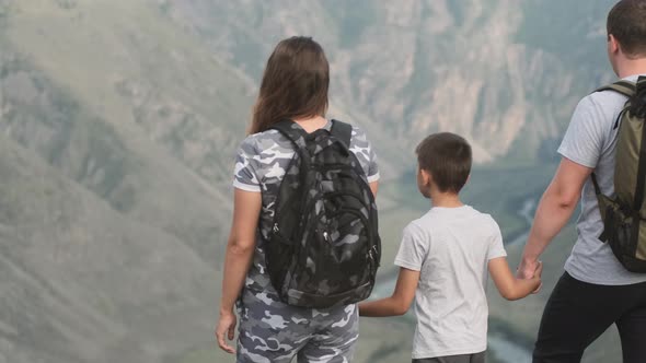 Happy Family of Travelers Man Woman and Child Come To the Edge of the Cliff and Look Forward