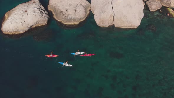 Aerial Tourists on Kayaks Sail on Sea Against Rocky Coast