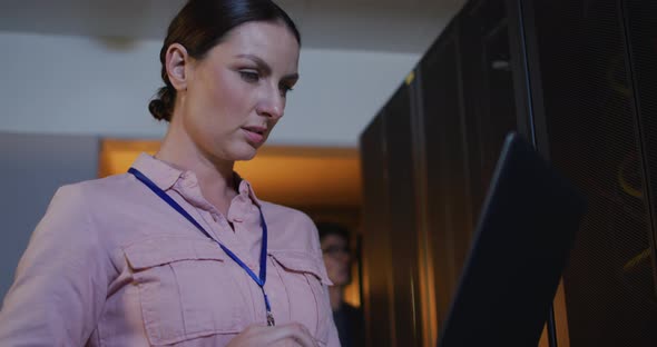 Caucasian female it technician using laptop checking computer server