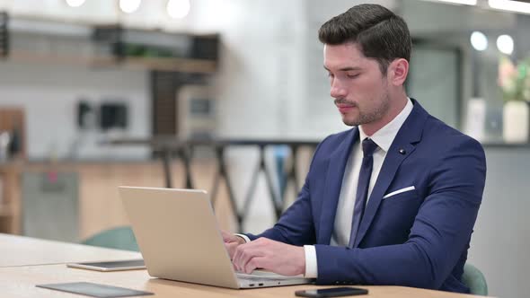 Excited Businessman Celebrating Success on Laptop in Office 