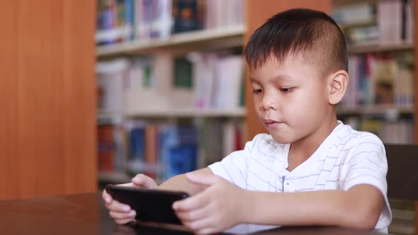 A boy sitting enjoying the phone in the library