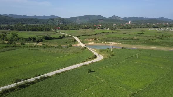 Aerial View Rural Road Across Large Field Against Mountains