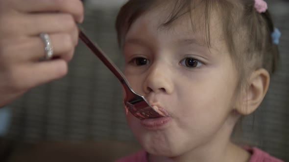 Mom Feeding Little Daughter Cake with Fork