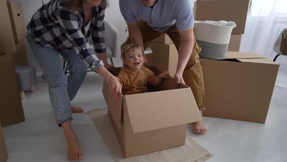 Husband and Wife Ride a Happy Child in a Cardboard Box