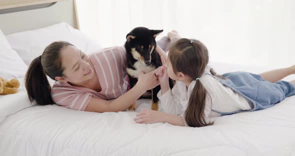 Mother and daughter playing with black dog on bed (6)