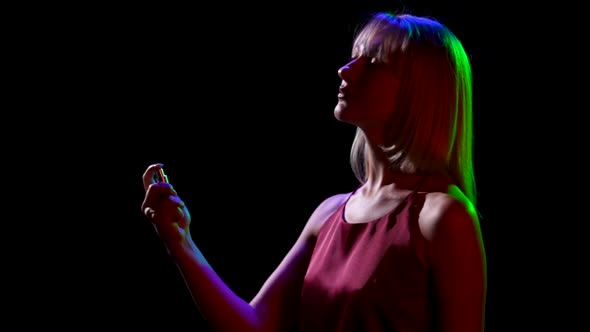 Side View of a Silhouette of Young Pretty Blonde Sprinkling Perfume on Herself From a Spray Bottle