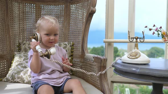 Cute Little White Girl Sitting in a Chair Talking on a Vintage Corded Phone