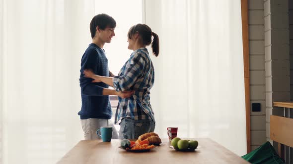 Cheerful Students Girl and Guy Are Dancing and Kissing in Kitchen Listening To Music at Home