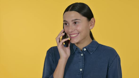 Latin Woman Talking on Smartphone Yellow Background