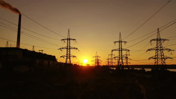 Industrial zone at sunset. High-voltage electric lines near factory 