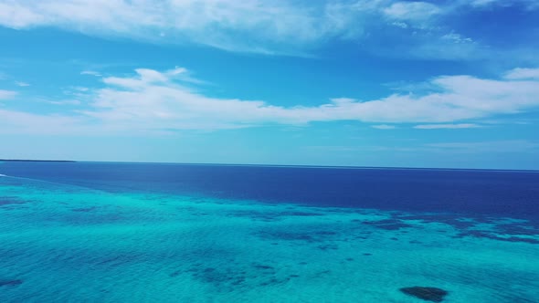 Tropical flying tourism shot of a sandy white paradise beach and aqua blue ocean background in best 