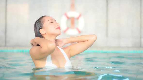 Hot Attractive Asian Woman Pushing Back Wet Hair In Swimming Pool - bust shot