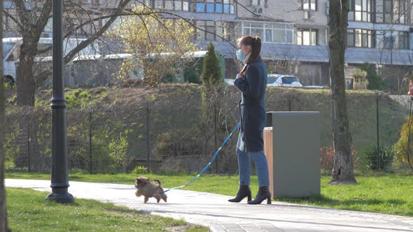 Slim Lady in Medical Mask Walks with Lovely Terrier Puppy