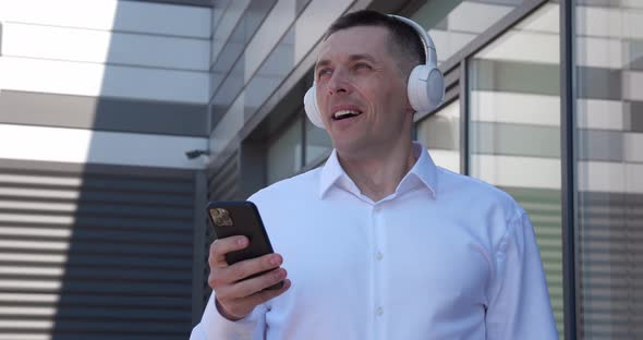 Portrait of 40 Years Old Man Enjoy Listen Music By Wireless Headphones and Smartphone Standing