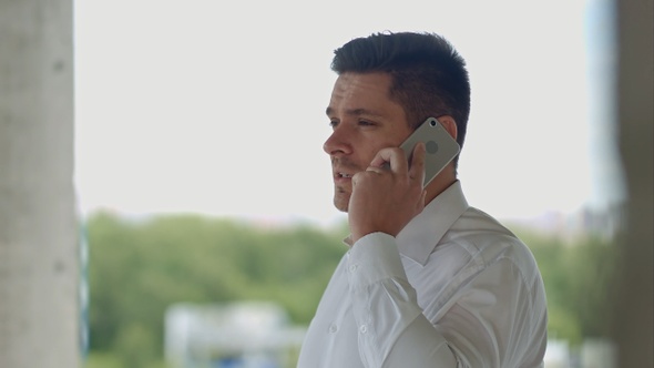 Architect talking by phone standing at construction site