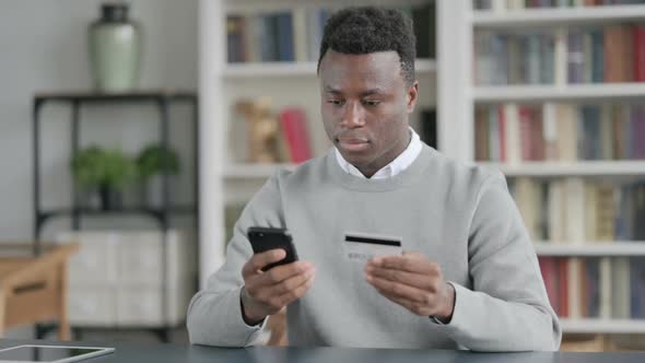 African Man Making Online Payment on Smartphone