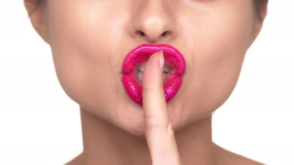 Extreme Closeup Portrait of Woman Holding Index Finger on Plump Lips Covered with Pink Lipstick