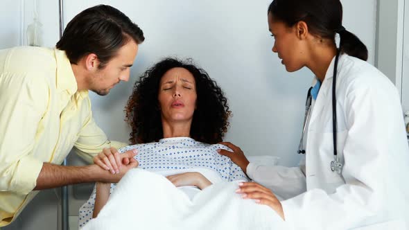 Doctor and man comforting pregnant woman in ward