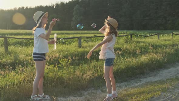 Children Blowing Soap Bubbles, Two Girls Playing in Nature