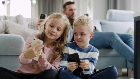 Handheld view of children using mobile phone in living room