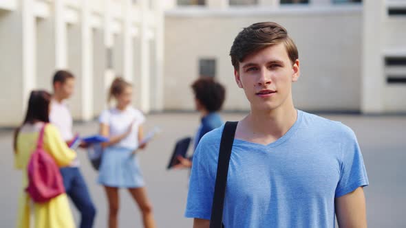 Young Man Student Looking at Camera Against College Building