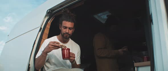 Young man enjoying food sitting in the back of a van