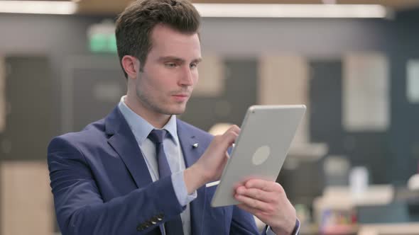 Portrait of Attractive Businessman Using Tablet in Office