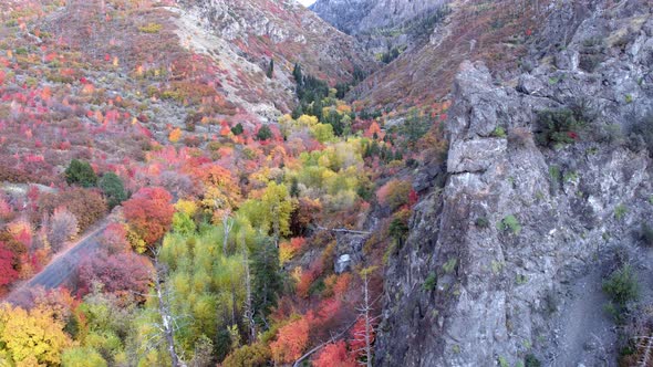 Flying plast rocky cliff face towards canyon in Fall color