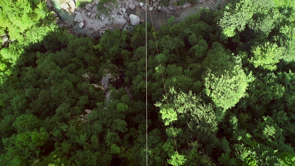 Aerial view of a person flying over the forest in zip-line at Slovenia