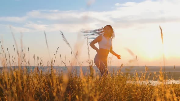 Woman with Long Blue Braids Dancing on Sunset Wheat Field