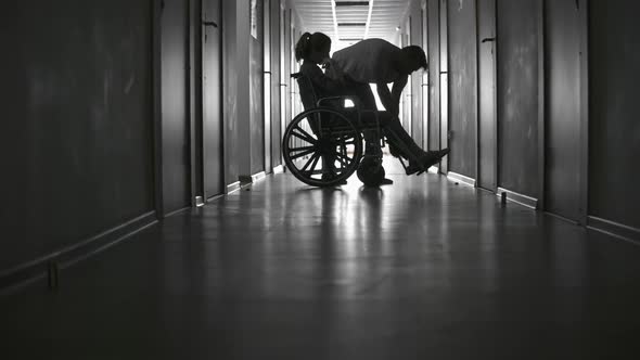 Unrecognizable Man Pushing Wheelchair of Ill Woman