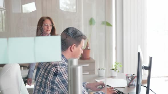 Middle Age Business Woman Talking with Her Young Team Leader in the Office