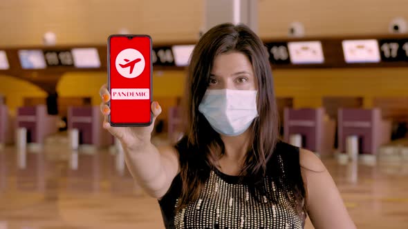 Woman, in Protective Mask, Holds Smartphone with COVID-19 Icon, Text - Pandemic, on Screen, in Front