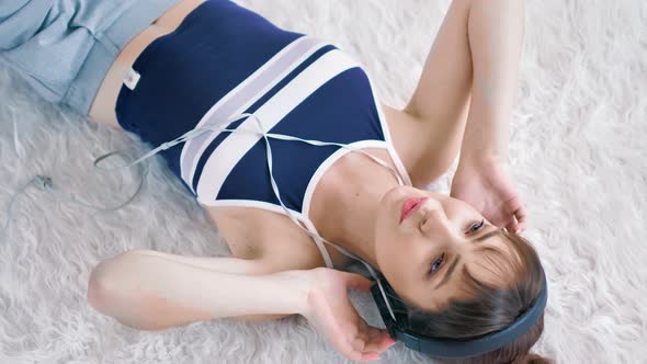 High Angle Young Woman Teenager Enjoying Favorite Music at Headphones Lying on White Fluffy Carpet