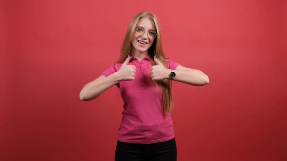 Portrait of Attractive Young Woman Showing a Thumbs Up on Red Background