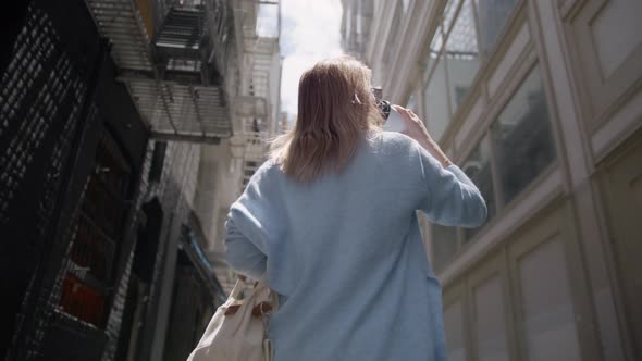 Back Following Shot of Young Woman Walking in Urban City Street Drinking Coffee