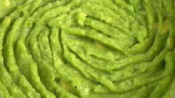 Guacamole dip rotating in glass bowl close up background. Cooking healthy food. Making avocado dip